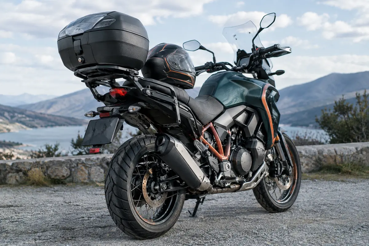 Moto équipée d’un top-case noir, avec un casque posé à côté pour illustrer le choix du volume.