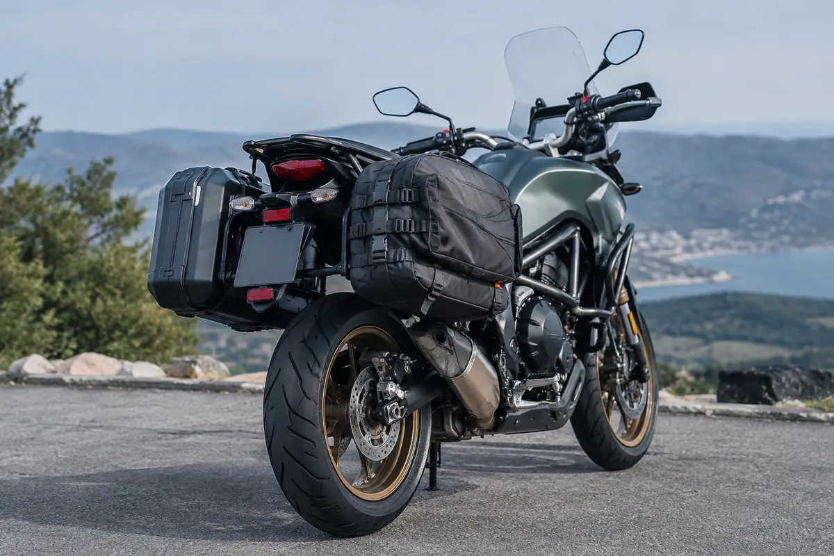 Moto de tourisme équipée de valises latérales rigides et souples, avec les fixations visibles