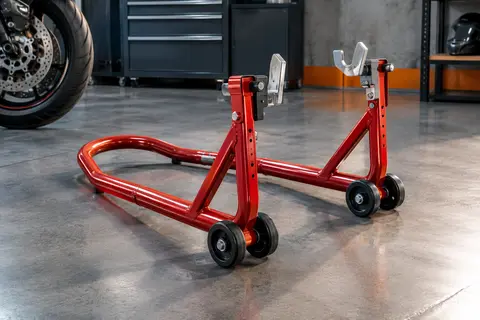 Béquille arrière rouge à quatre roues et embouts à fourche présentée dans un atelier moto soigné.