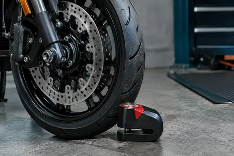 Bloque-disque moto compact noir et rouge en métal présenté près du disque de frein