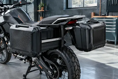 Valises latérales extensibles noires SH38X Carbon, présentées sur une moto dans un atelier soigné.