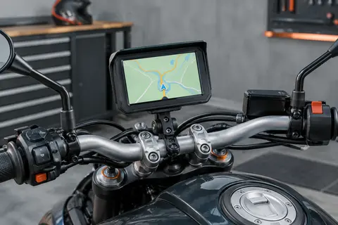 GPS moto noir à écran tactile installé sur son support dans un atelier sobre et soigné