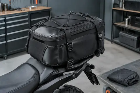 Sacoche de selle noire extensible installée sur une moto, avec ses sangles et sa housse de pluie